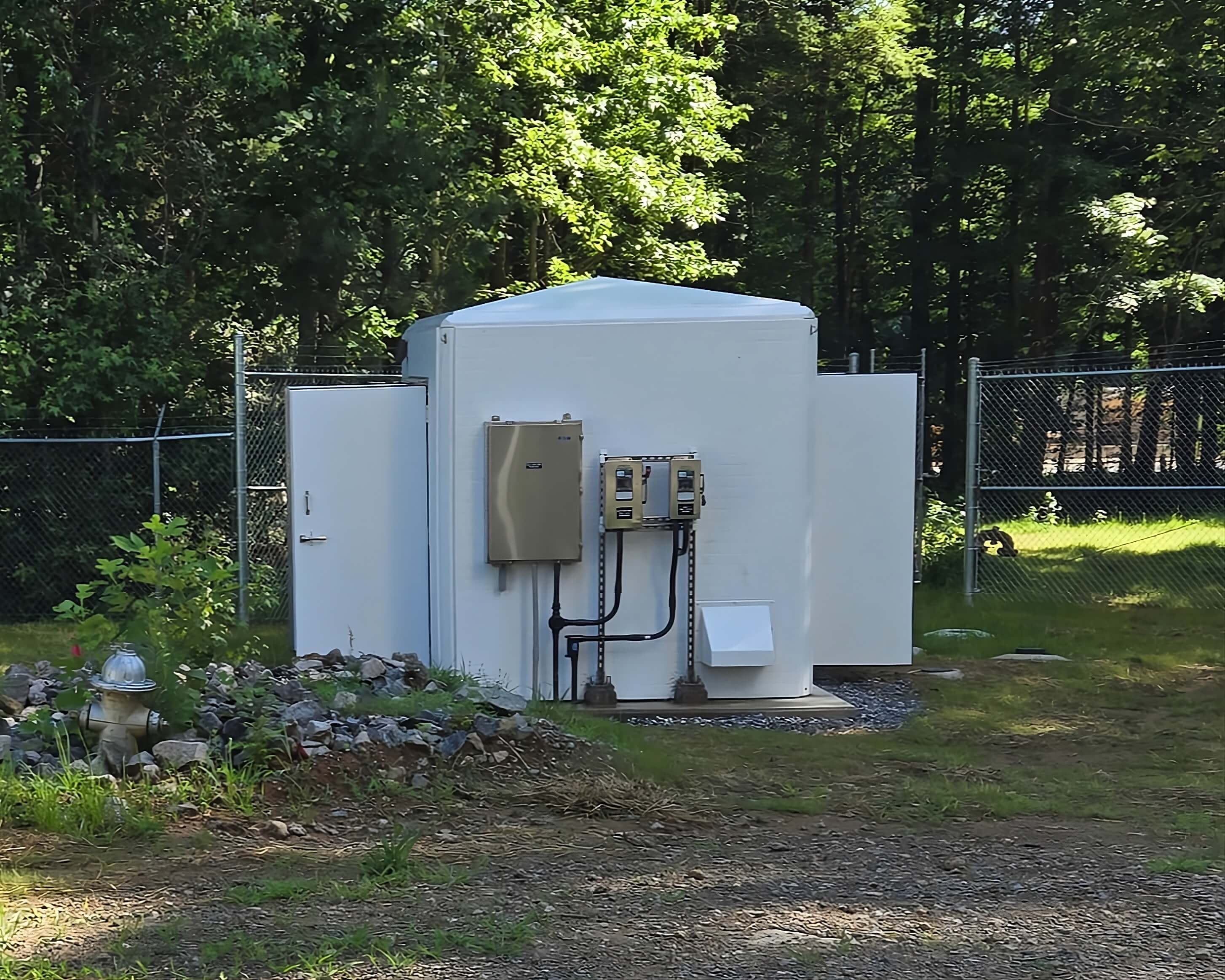 White FRP valve enclosure with exterior electrical panel protecting motorized butterfly valve at water storage tank