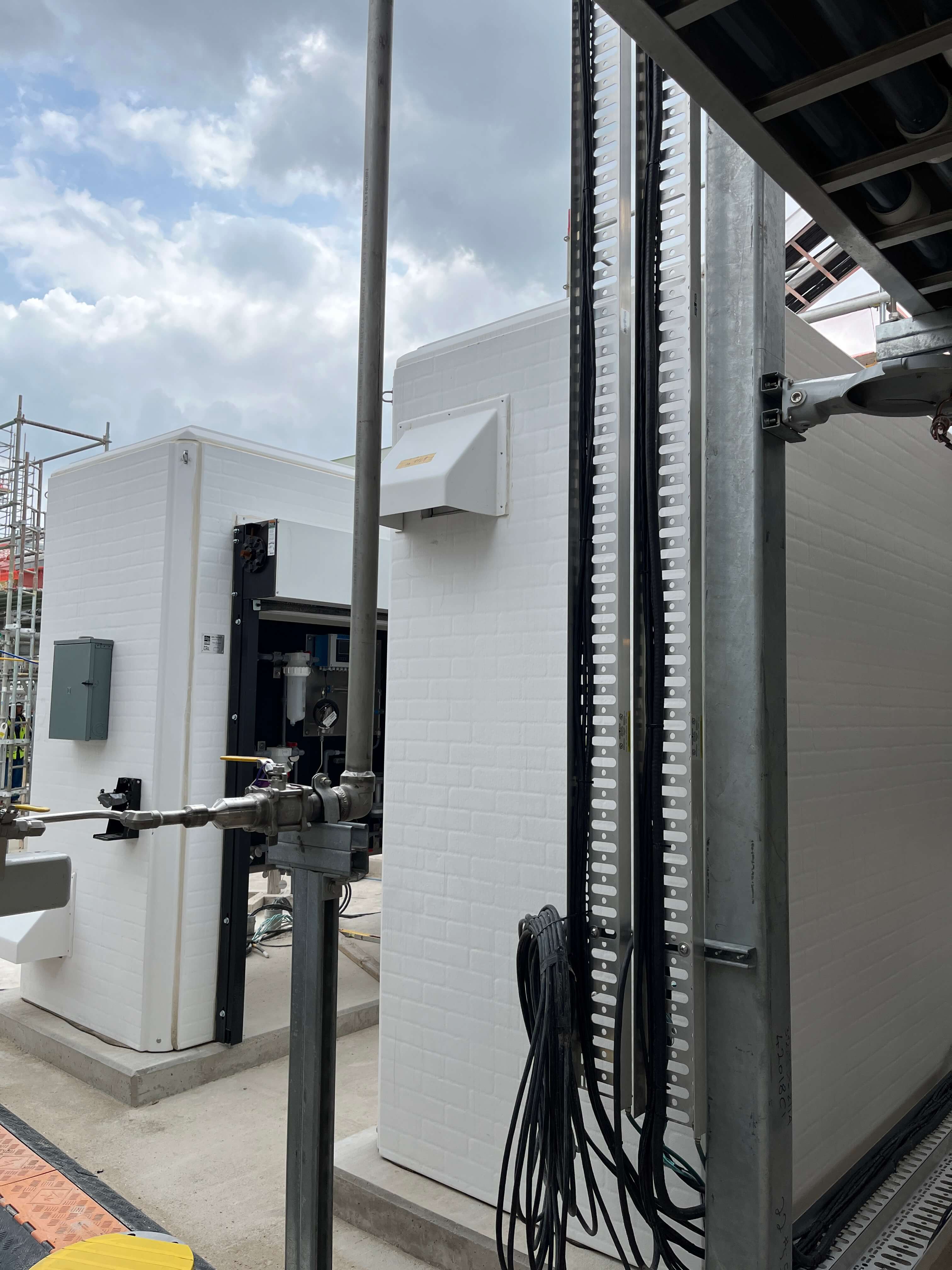 White fiberglass enclosure with removable panels and safety equipment for water reclamation systems