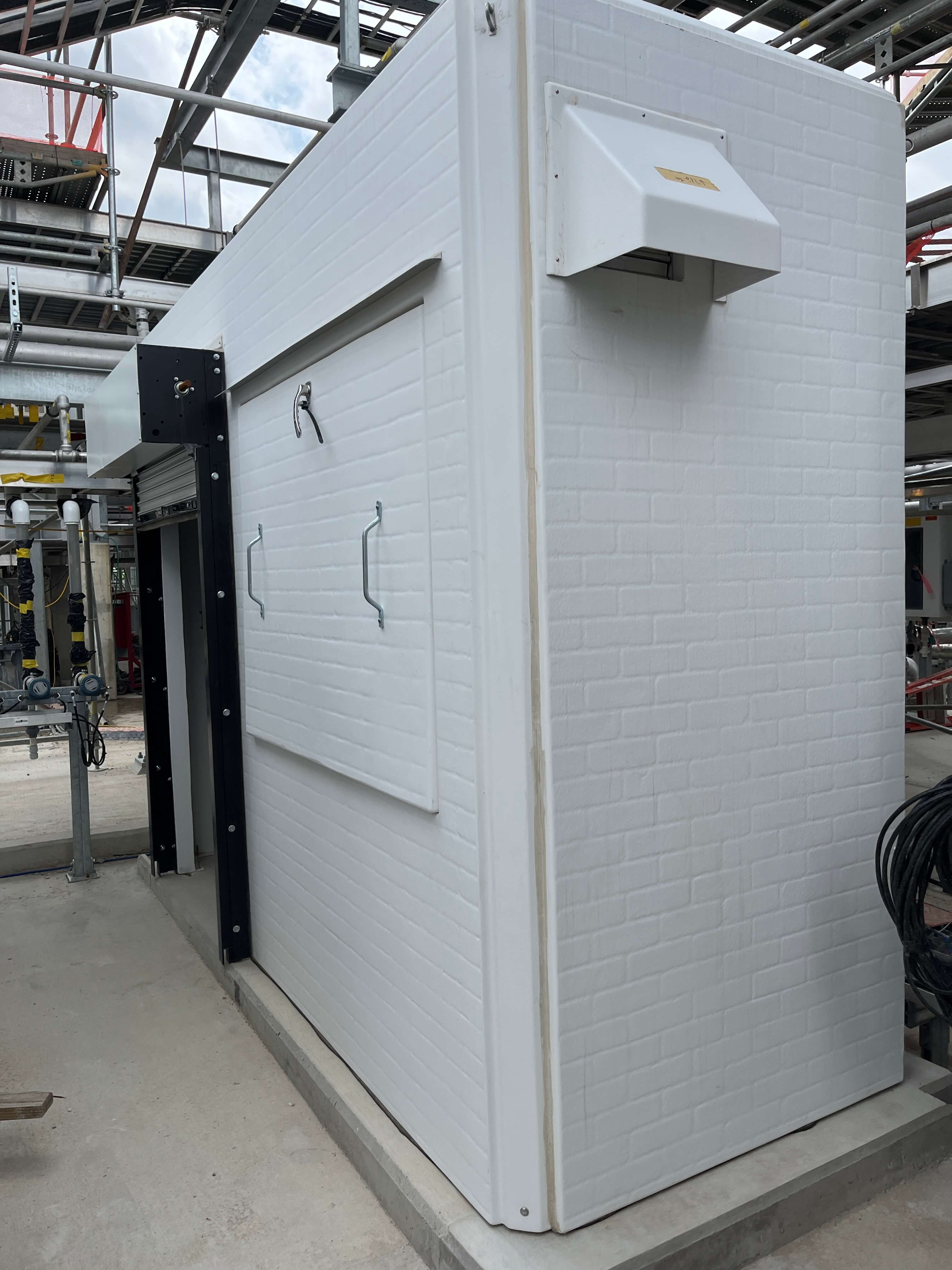 White fiberglass enclosure with removable panels and safety equipment for water reclamation systems