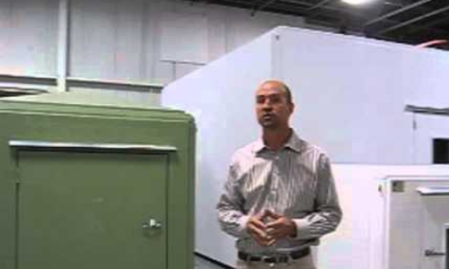 Tracy stands in front of several different sizes of shelter in a warehouse